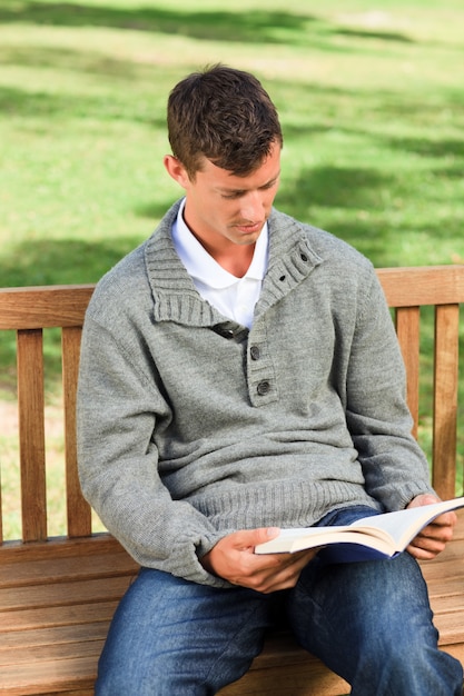 Uomo che legge il suo libro in panchina