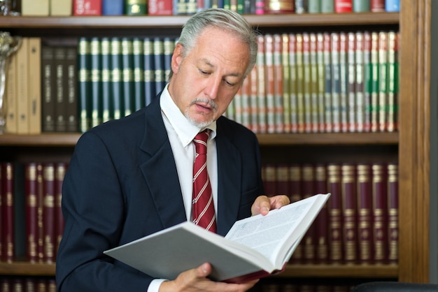 Uomo che legge un libro nella sua biblioteca