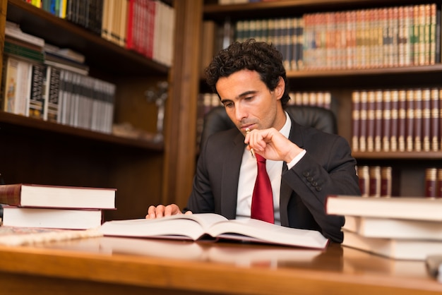 Uomo che legge un sacco di libri nel suo ufficio