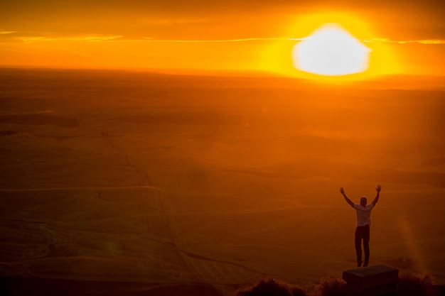 Uomo che levita contro il paesaggio durante il tramonto