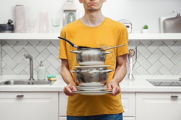 Uomo che maneggia la torre di utensili da cucina non lavati