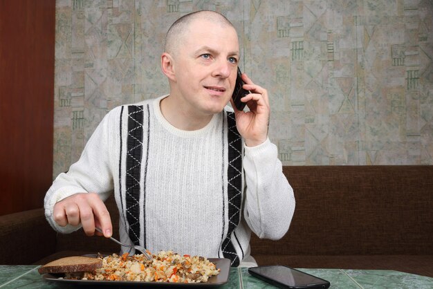 Uomo che mangia pilaf e parla su un telefono cellulare