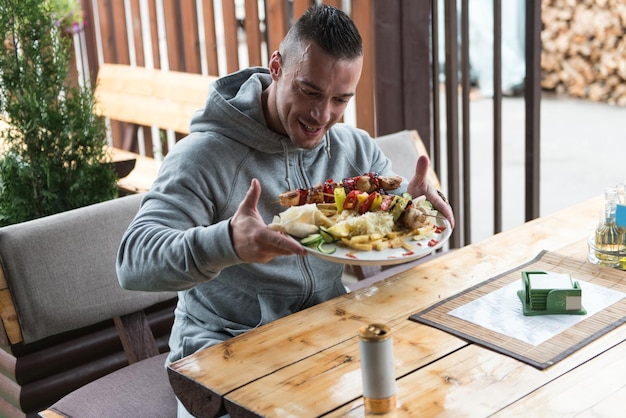 Uomo che mangia pollo con riso nel ristorante all'aperto