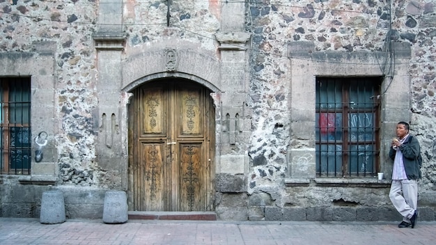 Uomo che mangia sulla facciata di un edificio con porta in legno e pietra messico