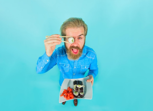 Uomo che mangia sushi uomo barbuto con piatto di sushi uomo con sushi su bacchette Giappone consegna sushi