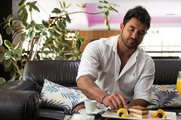 Uomo che mangia una torta in un bar della hall dell'hotel