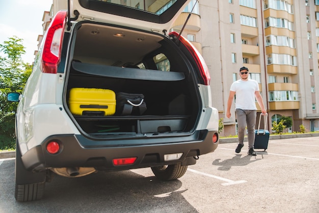 Uomo che mette le borse nel bagagliaio dell'auto pronto per il viaggio in auto