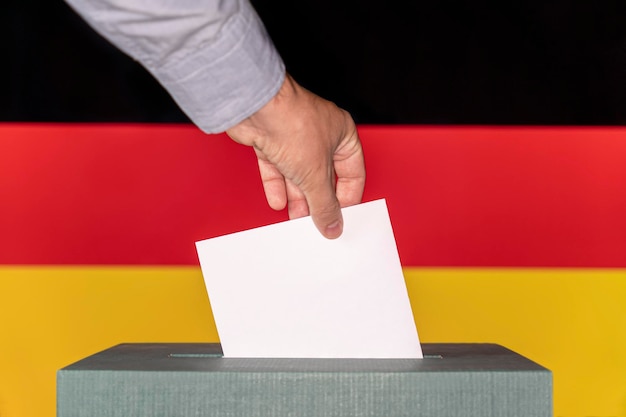 Uomo che mette una scheda elettorale in una casella di voto sullo sfondo della bandiera Germania