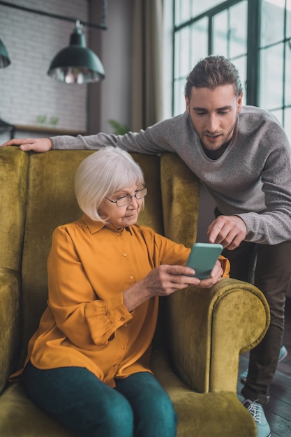 Uomo che mostra a sua madre come utilizzare lo smartphone