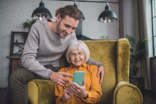 Uomo che mostra a sua madre come utilizzare lo smartphone