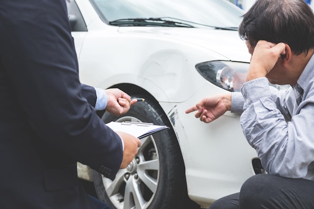 Uomo che mostra l'auto danneggiata all'agente assicurativo