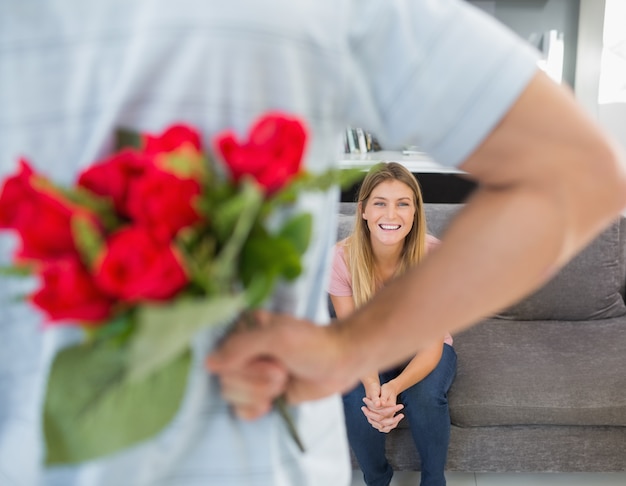 Uomo che nasconde il mazzo di rose dalla fidanzata sul divano