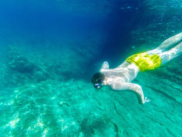 Uomo che nuota sott'acqua con occhiali subacquei