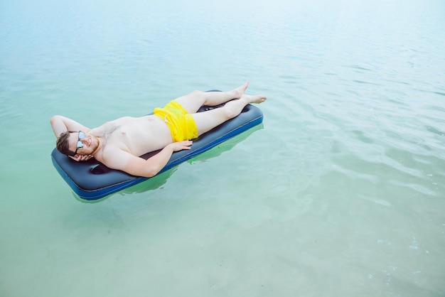 Uomo che nuota sul materasso in mare