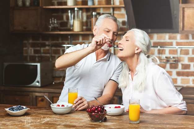 Uomo che nutre donna con ciliegie in cucina