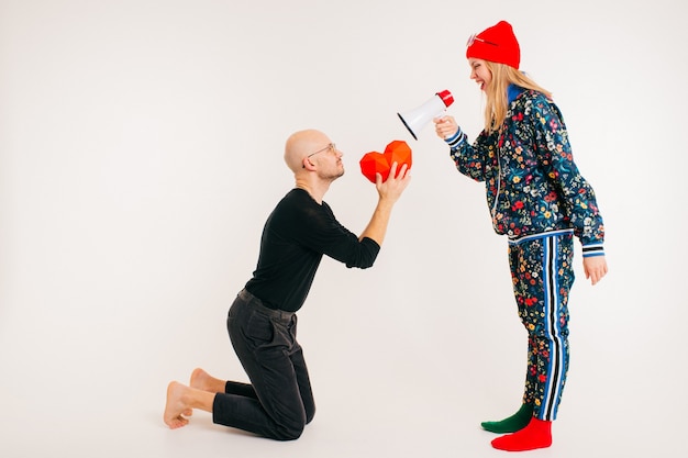 Uomo che offre cuore alla donna alla moda su sfondo bianco