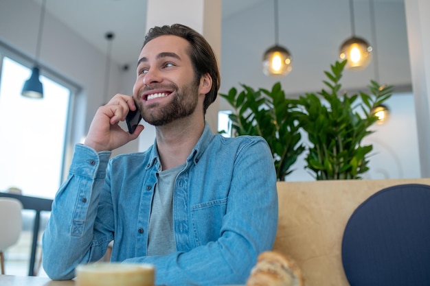 Uomo che parla su smartphone seduto al chiuso durante il giorno