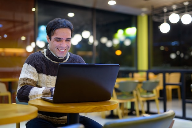 Uomo che per mezzo del computer portatile alla caffetteria