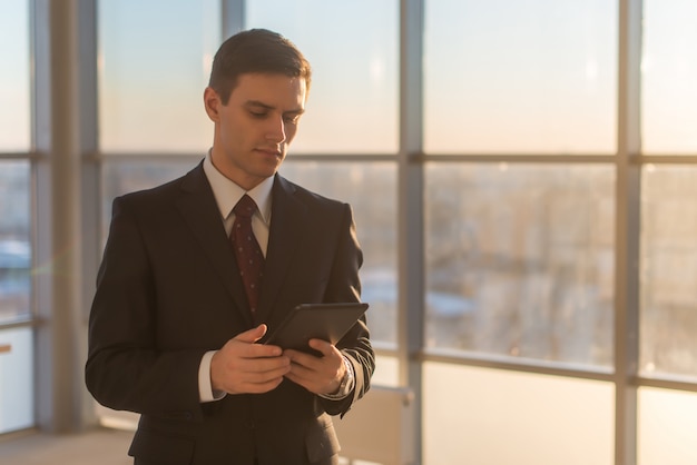 Uomo che per mezzo della compressa digitale al suo posto di lavoro