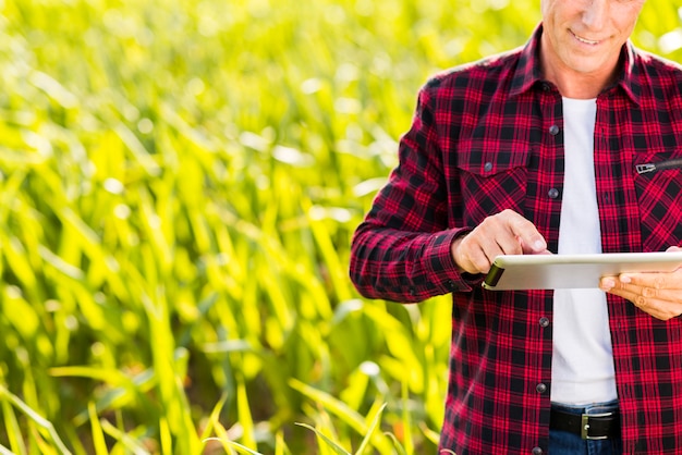 Uomo che per mezzo di una compressa su un campo di mais