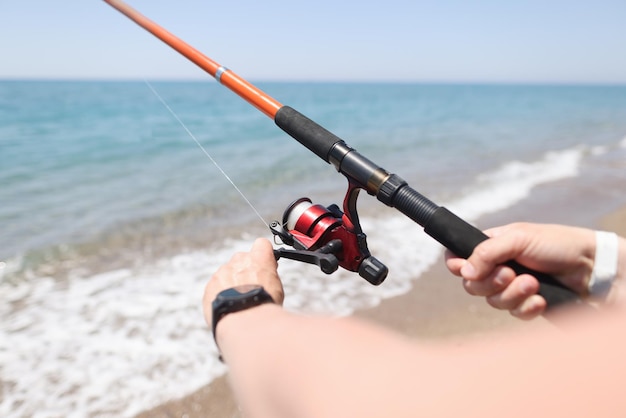 Uomo che pesca con la canna sul primo piano della spiaggia