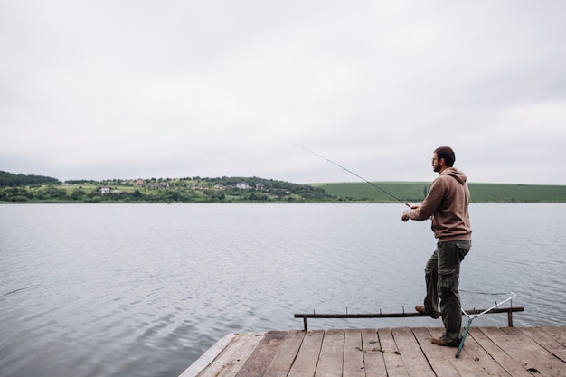 Uomo che pesca nel lago calmo