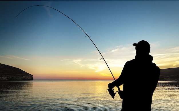 Uomo che pesca sul fiume il giorno d'estate