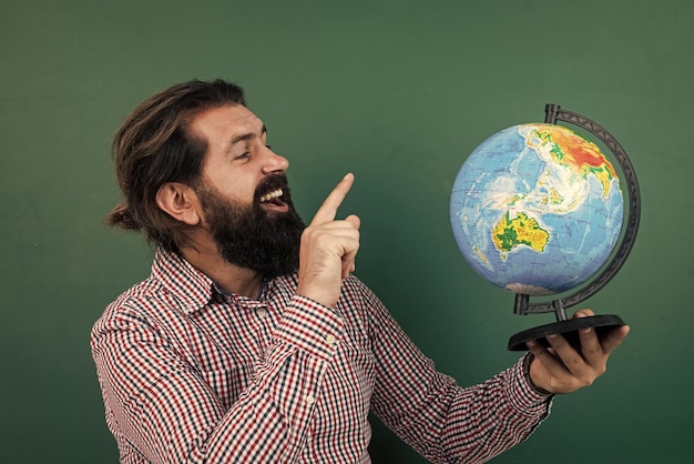 Uomo che pianifica le vacanze guardando il globo geografico in gita scolastica