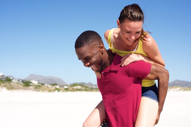 Uomo che porta la donna sulla schiena in spiaggia