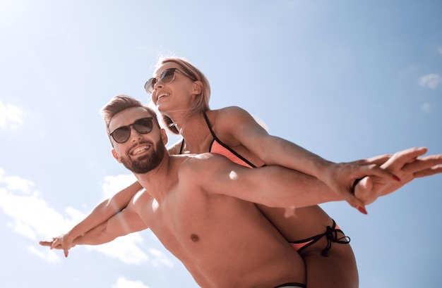 Uomo che porta la donna sulle spalle sulla spiaggia