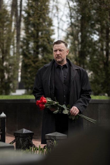 Uomo che porta rose su una lapide al cimitero