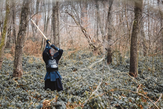 Uomo che pratica kendo con spada di bambù shinai sullo sfondo della foresta