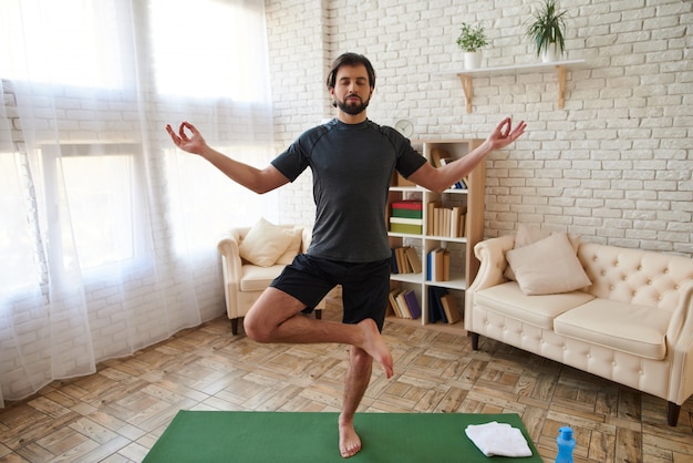 Uomo che pratica yoga avanzato a casa. Esercizi sportivi.