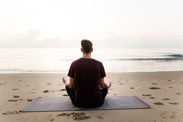 Uomo che praticano yoga sulla spiaggia