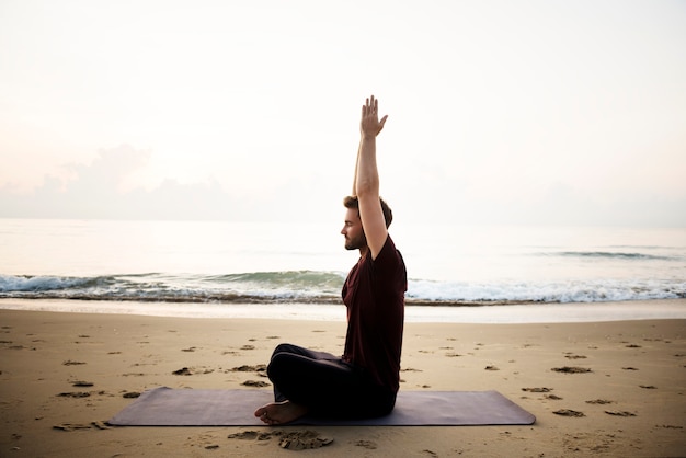 Uomo che praticano yoga sulla spiaggia