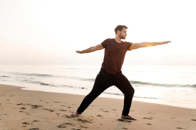 Uomo che praticano yoga sulla spiaggia