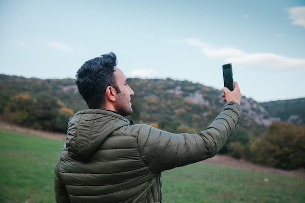 Uomo che prende selfie all'aperto nel campo in autunno