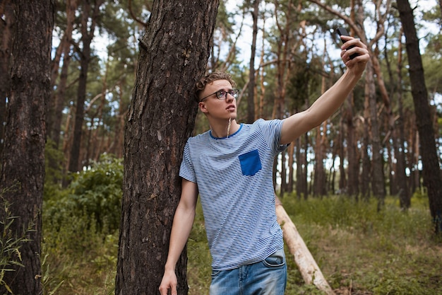 uomo che prende selfie sul telefono nella foresta. solo con la natura. stile di vita del viaggiatore.