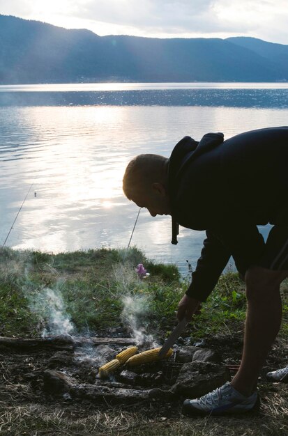 Uomo che prepara il mais al lago al barbecue