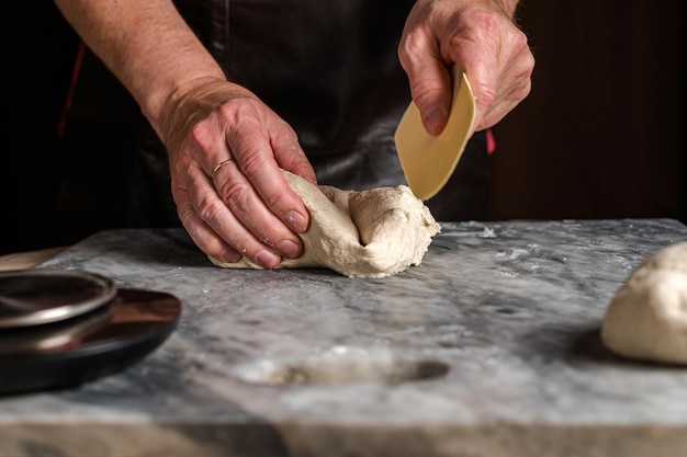 Uomo che prepara la pasta della pizza sul tavolo di marmo