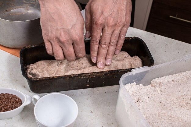 Uomo che prepara la pasta di pane sulla tavola di legno.