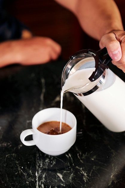 Uomo che produce caffè con latte