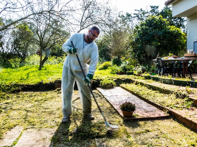 Uomo che pulisce con scopa di ferro in giardino