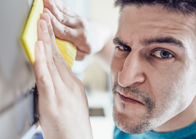 Uomo che pulisce i mobili della cucina