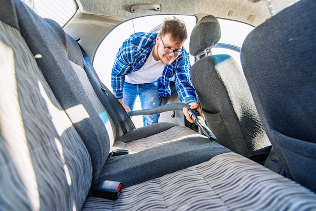 Uomo che pulisce l'auto con il concetto di autolavaggio aspirapolvere