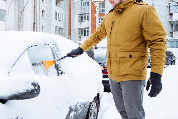 Uomo che pulisce l'auto dopo la tempesta di neve