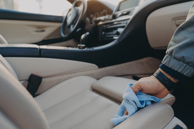 Uomo che pulisce l'interno dell'auto con un panno in microfibra al servizio di autolavaggio