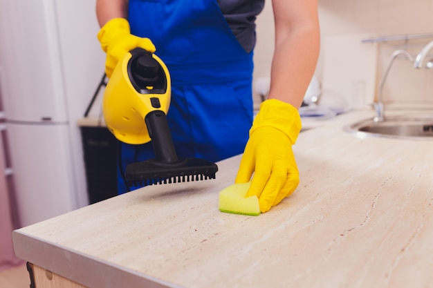 Uomo che pulisce la cucina con spugna pulitore a vapore.