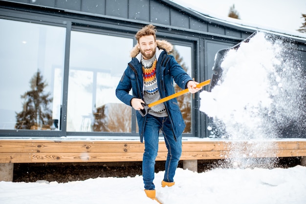 Uomo che pulisce la neve vicino alla casa