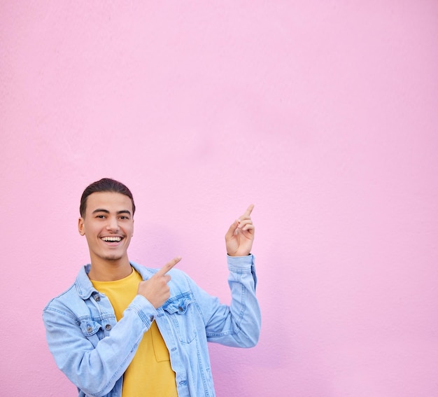 Uomo che punta lo spazio del mockup del muro e sorride per il ritratto con il viso felice ed eccitato della moda sullo sfondo Gesto del modello Gen z e mani con felicità mock up e studente sullo sfondo rosa urbano